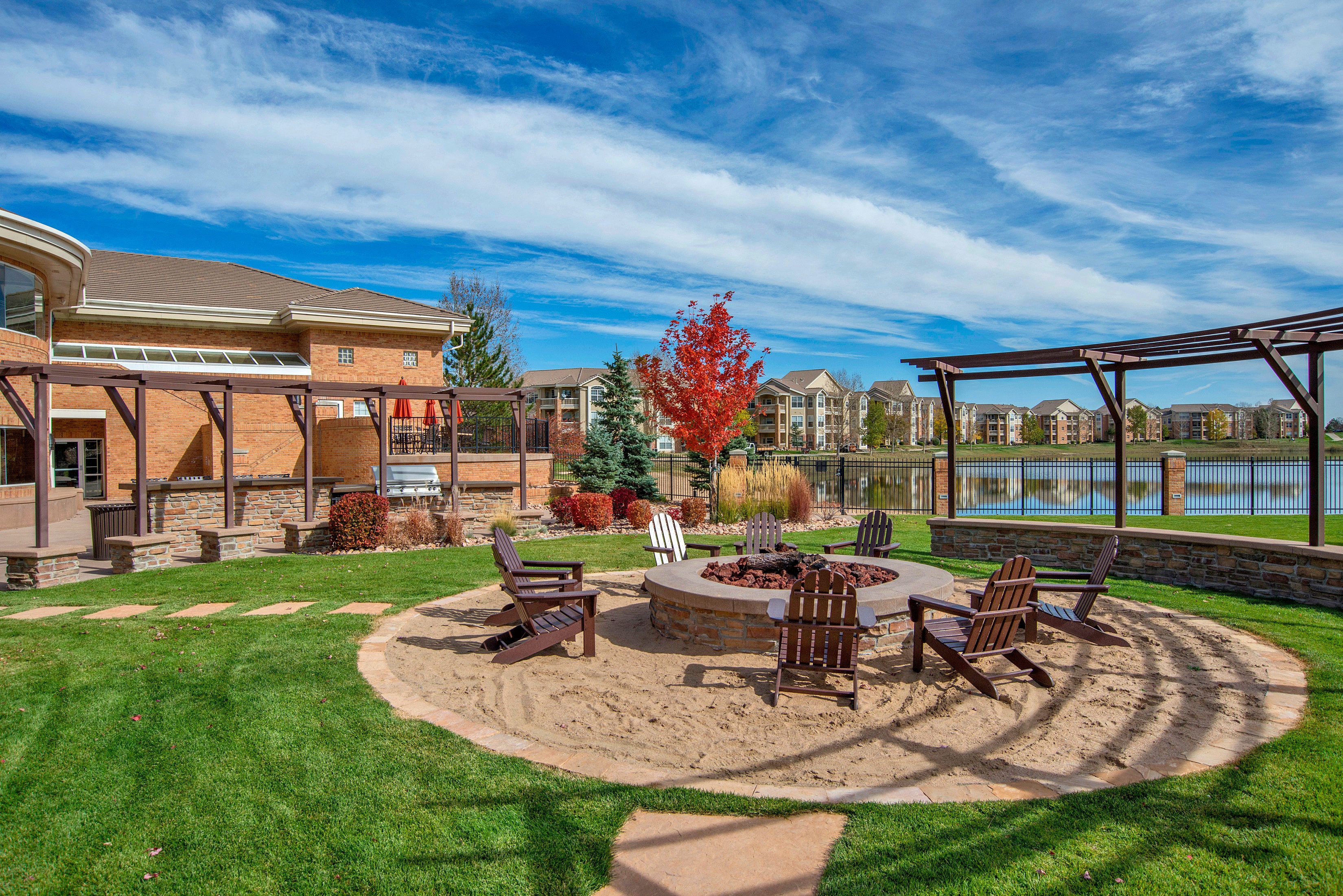 A backyard with a fire pit and chairs.